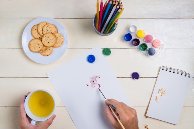 Borstel, schetsboek en aquarel kleuren op tafel.