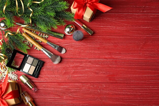 Borstels met kleurrijke make-upcosmetica en ingepakte geschenken op rood houten oppervlak