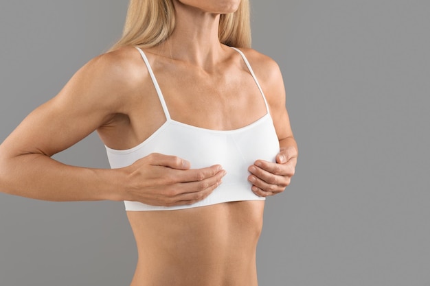 Borstvergroting concept onherkenbaar vrouw in witte top aanraken borstgebied