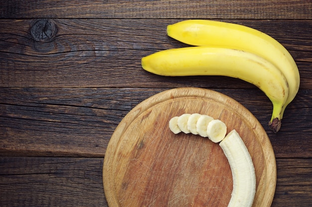 Bos van bananen en een gesneden op een donkere houten tafel, bovenaanzicht