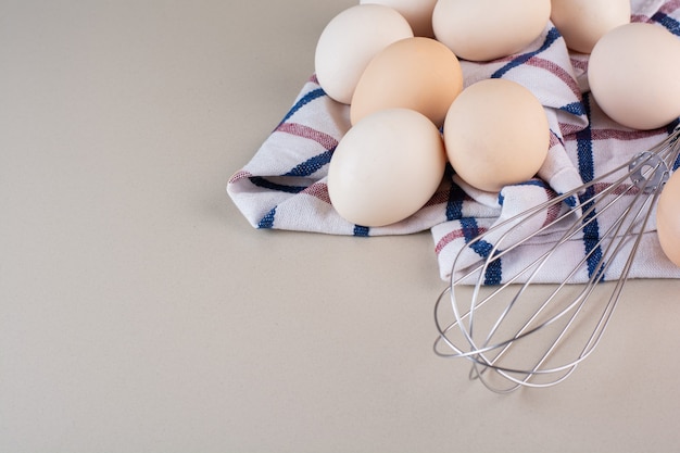 Bos van biologische rauwe eieren met bakkebaard op beige tafel.