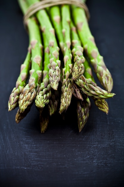 Bos van de verse ruwe close-up van de tuinasperge op zwarte raadsachtergrond.