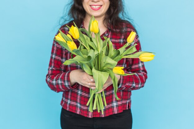 Bos van gele tulpen op de handen van de vrouw op blauwe muur