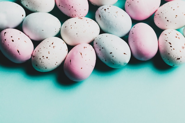 Bos van kleurrijke eieren die op een pastelkleur blauwe achtergrond leggen.