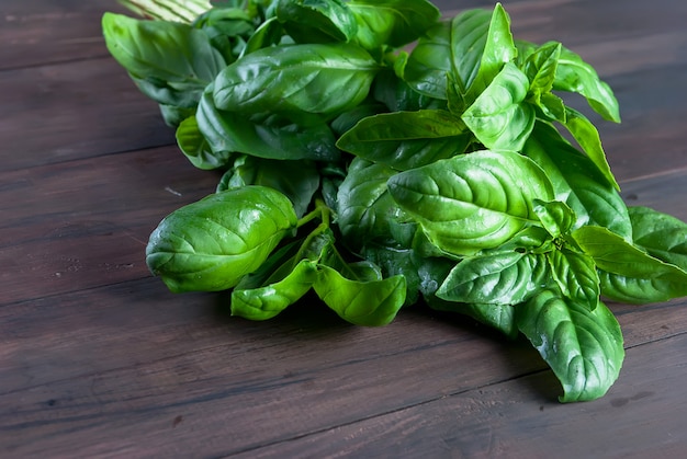 Bos van vers groen basilicum op een donkere houten achtergrond