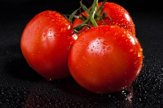 Bos van verse rijpe rode tomaten met dropsGroenten op een donkere achtergrond