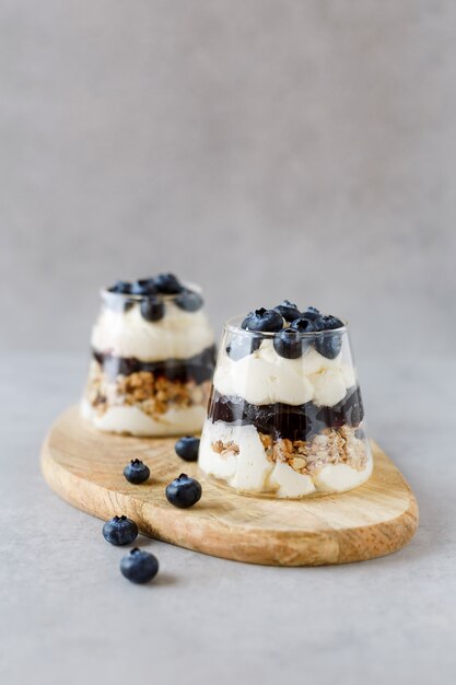 Bosbessendessert met gestremde melkroom en granola op de houten tribune