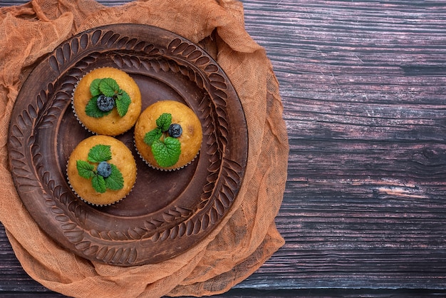 Bosbessenmuffins in bruine plaat op donker hout. bovenaanzicht.