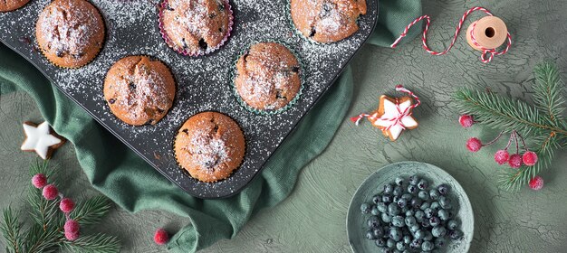 Bosbessenmuffins met suikerglazuur in een bakplaat. Panoramisch bovenaanzicht met kerstdecor