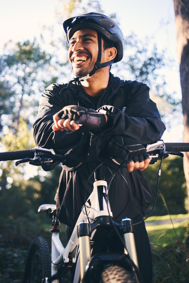 Foto bosfitness en glimlach fietser op de fiets in de natuur met helmoefening avonturenparcours en gezonde mentaliteit fietsen ontspannen en man met mountainbike in bomen voor training, motivatie of energie