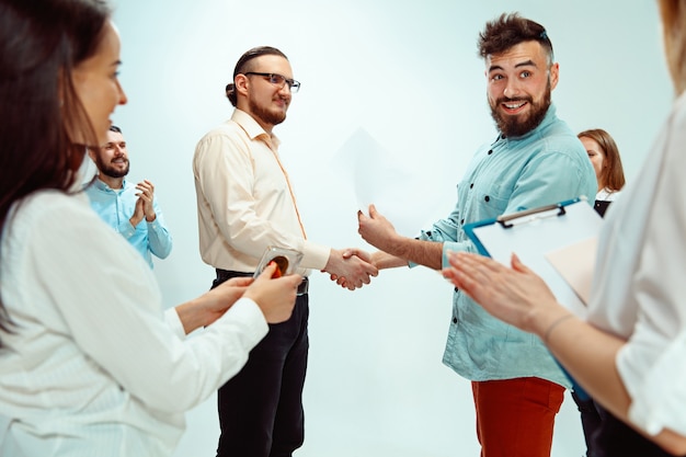 Boss approving and congratulating young successful employee