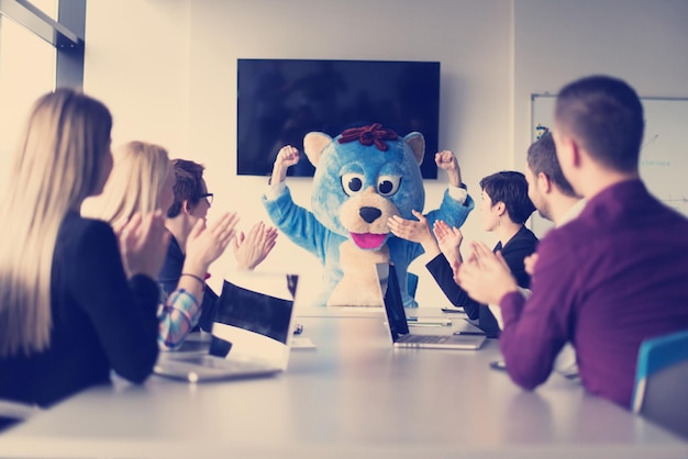 Boss dresed as teddy bear having fun with bussines people in modern corporate office