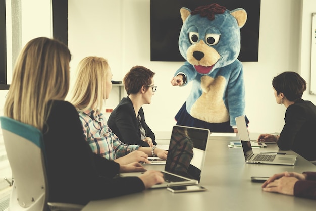 Boss dresed as teddy bear having fun with bussines people in modern corporate office