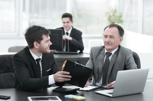 Boss and employee discussing the document sitting at the desk in the office