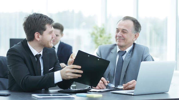 Boss and employee discussing the document sitting at the desk