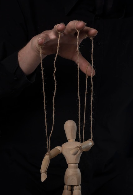 Boss hand manipulating and controling wood marionette master of puppet concept