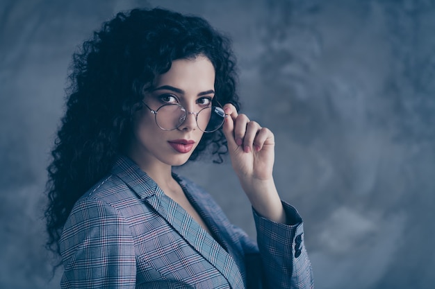 Boss lady touching specs isolated over concrete wall