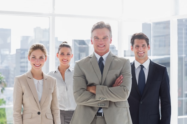 Boss with his arms folded standing with smiling colleagues behind