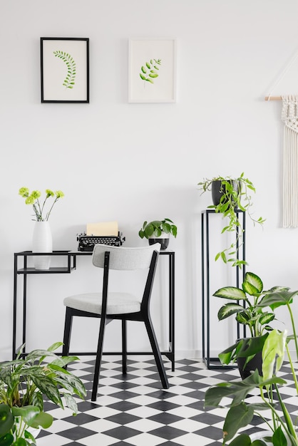 机の椅子と壁にグラフィックが描かれた植物のホームオフィスのインテリア 本物の写真