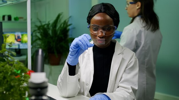 Botanicus onderzoeker wetenschapper die groene vloeistofmonsters onder de microscoop analyseert voor microbiologisch experiment. Chemicusspecialist die biologische ggo-planten ontdekt terwijl hij in een farmaceutisch laboratorium werkt