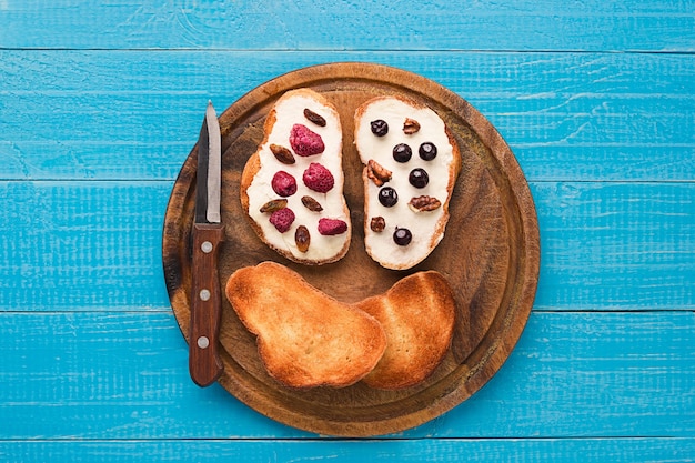 Boterbroodjes op gezond volkorenbrood belegd met verse frambozen, krenten en rozijnen. Bovenaanzicht. Stilleven. Ruimte voor tekst.