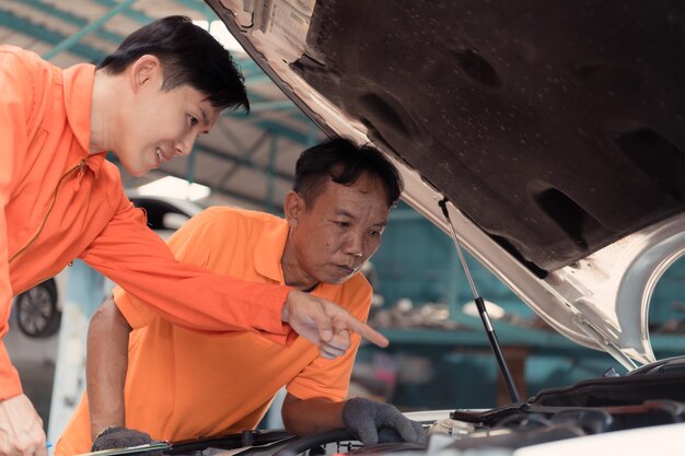 写真 両方の自動車整備士が、修理のためにガレージに持ち込まれた顧客の車のエンジンを検査しています。