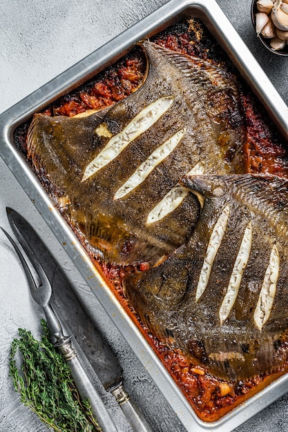 Botplatvis geroosterd in tomatensaus in bakplaat. Witte achtergrond. Bovenaanzicht.