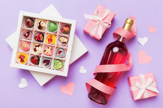 Bottel rode wijn op gekleurde achtergrond voor Valentijnsdag met geschenk en chocolade Hartvormig met geschenkdoos chocolade bovenkant met kopieerruimte