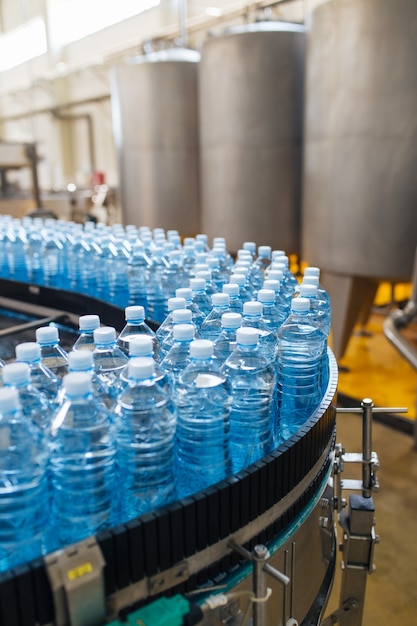 Bottelinstallatie - Waterbottellijn voor het verwerken en bottelen van zuiver bronwater in blauwe flessen. Selectieve aandacht.