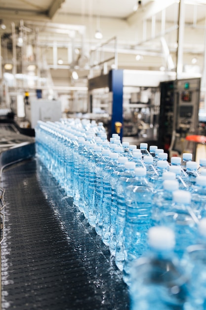 Bottelinstallatie - Waterbottellijn voor het verwerken en bottelen van zuiver bronwater in blauwe flessen. Selectieve aandacht.