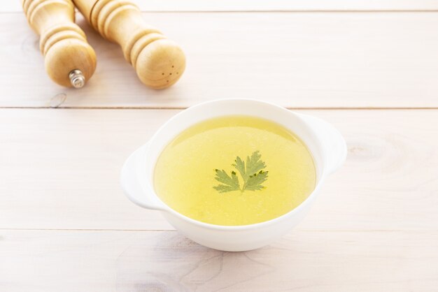 Bottenbouillon met peterselie in een kom op een houten tafel