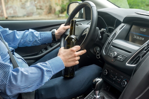 Bottle of alcohol beverage in driver hands