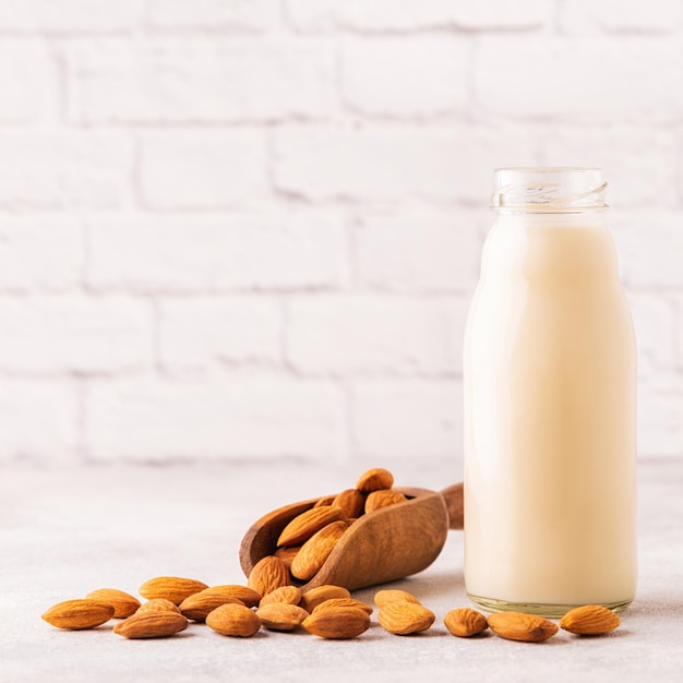 A bottle of almond milk and almonds on a light background.