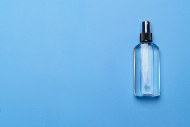 Bottle of antiseptic alcohol hand sanitize spray on a blue background for the prevention of coronavirus - flat layout with copy space