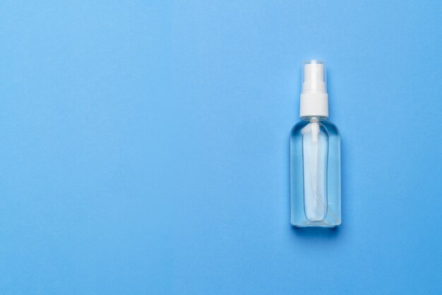 Bottle of antiseptic alcohol hand sanitize spray on a blue background for the prevention of coronavirus - flat layout with copy space