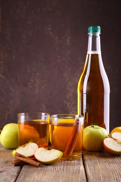 bottle of apple vinegar with fresh apples on wooden table