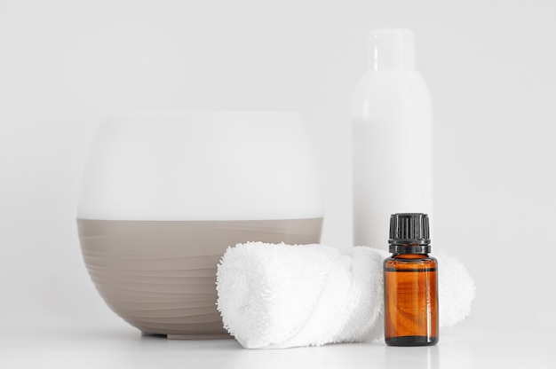 A bottle of aromatic oil a diffuser a towel on a white background