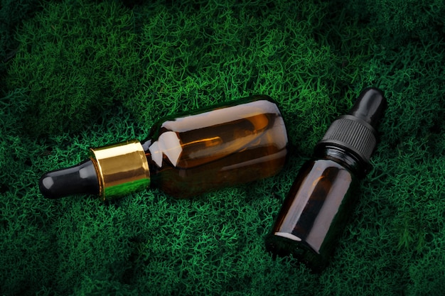 Bottle of aromatic oil for herbal medicine among natural green moss