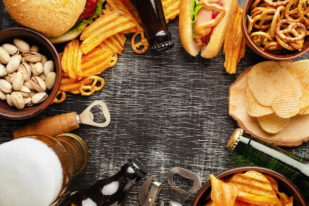 Bottle of beer and different snacks on rustic wooden table Top view