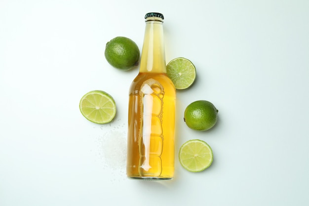 Bottle of beer, limes and salt on white background