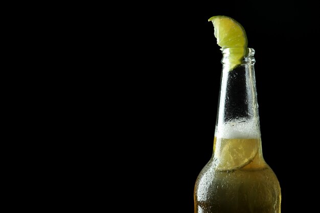 Bottle of beer with lime on black