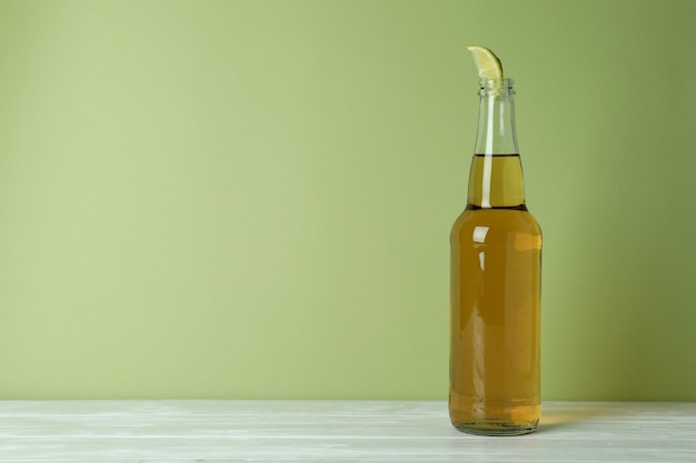 Photo bottle of beer with lime slice against green