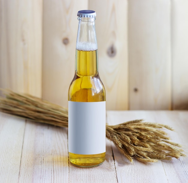 Bottle of beer with wheat on wooden background