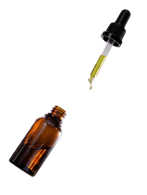 A bottle of cannabis oil and a dropper falling down isolated in white background