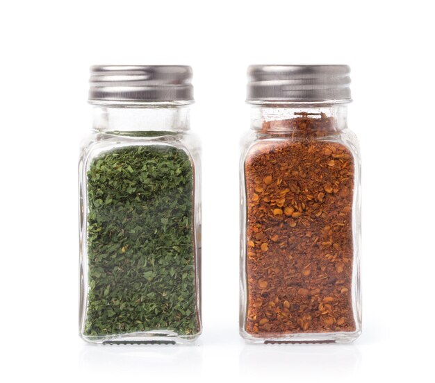 Photo bottle of cayenne pepper and dried parsley isolated on white background