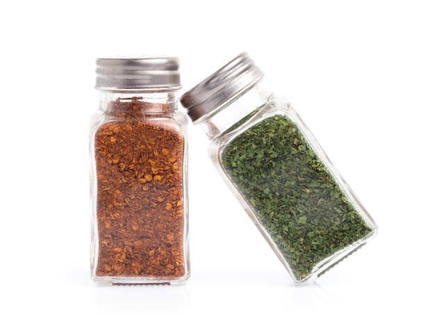 bottle of cayenne pepper and dried parsley isolated on white background