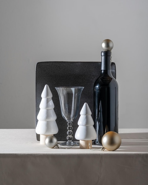 a bottle of champagne, Christmas trees made of wood, golden balls, a square black plate