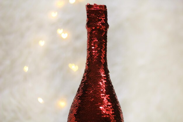 Photo a bottle of champagne decorated with sequins with heart-shaped in the background