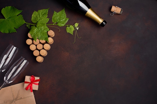 Bottiglia di champagne, grappolo d'uva di sughero con foglie, contenitore di regalo del bicchiere di vino su fondo arrugginito