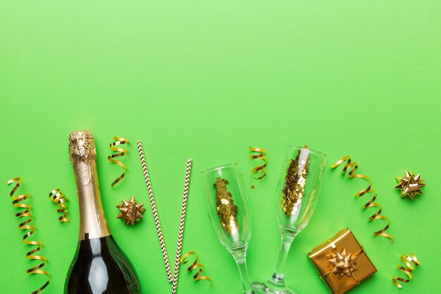 色付きのキラキラ紙吹雪とカラフルな背景のトップ ビューのテキストのギフト ボックス スペースとシャンパンのボトル陽気なクリスマスと誕生日のお祝い